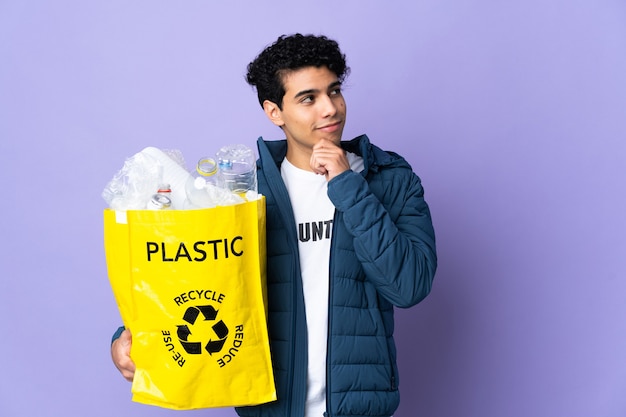 Joven venezolano sosteniendo una bolsa llena de botellas de plástico y mirando hacia arriba