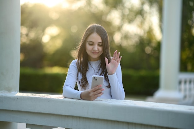 Una joven veraniega con un teléfono hablando por teléfono con una camiseta blanca