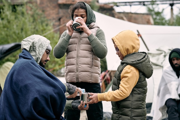 Joven vertiendo agua en la taza de su hija