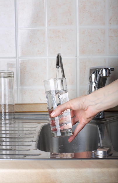 Foto la joven está vertiendo un poco de agua filtrada en el vaso. primer plano