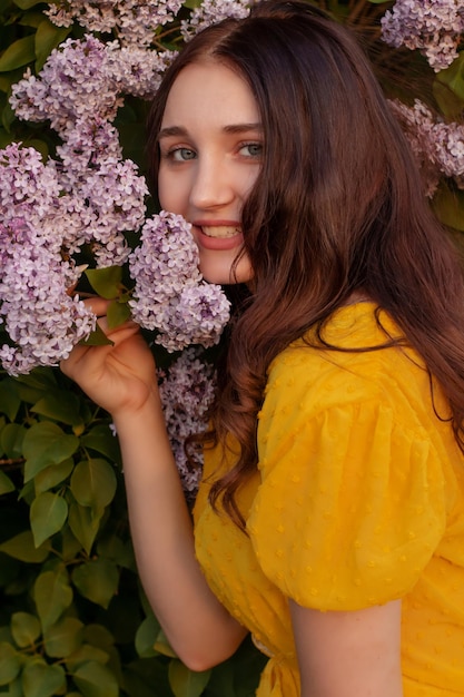 una joven con un vestido amarillo huele lila