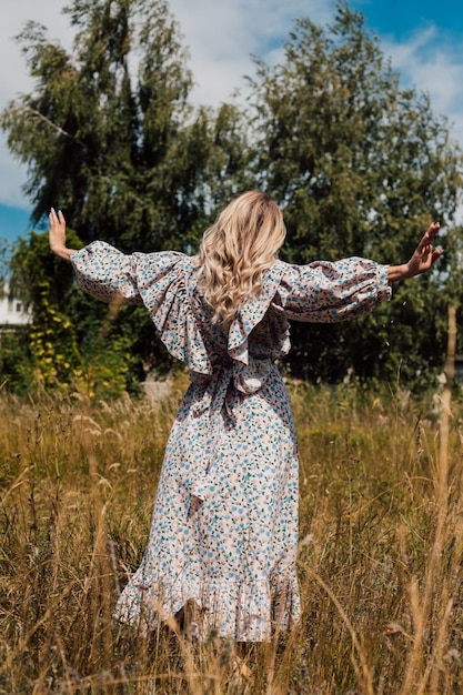 Una joven con un vestido largo camina por el campo.