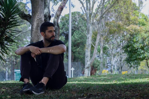 joven vestido con ropa atlética sentado en el parque practicando yoga