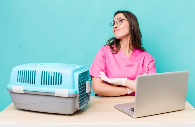 joven veterinaria bonita con una laptop y una jaula para mascotas