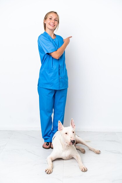 Joven veterinaria inglesa con perro aislado de fondo blanco apuntando hacia un lado para presentar un producto