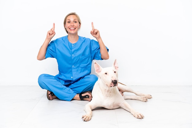 Joven veterinaria inglesa sentada en el suelo con un perro señalando una gran idea