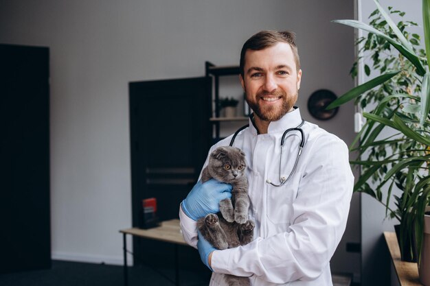 Foto joven veterinario con gato en la clínica