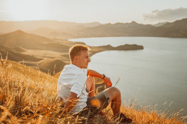 Un joven viaja a lo largo de la costa de la montaña al atardecer Un hombre se encuentra en la ladera de una montaña