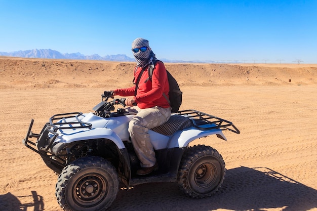 Joven en un viaje de safari por el desierto egipcio conduciendo ATV. Safari en quads en el desierto cerca de Hurghada, Egipto