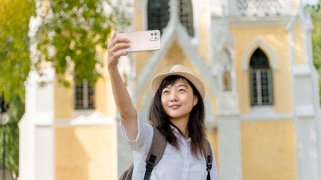 Joven viajera asiática usando teléfono móvil tomando selfie en el templo de ayutthaya tailandia Concepto de relajación de vacaciones de viaje