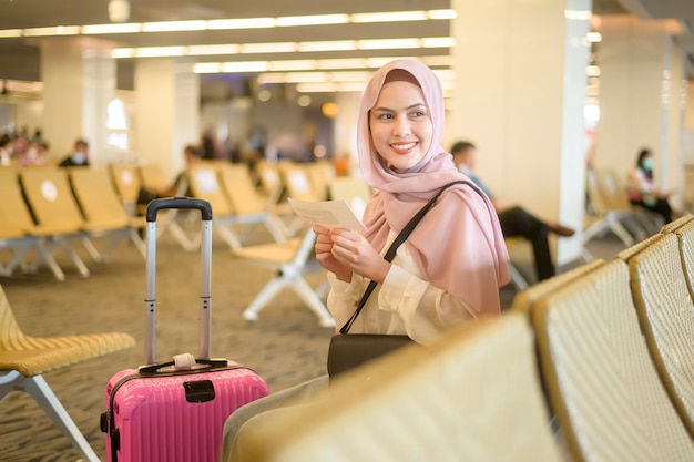 Joven viajera musulmana llevando maletas en el aeropuerto internacional