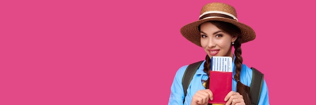 Foto joven viajera con ropa informal y sombrero de paja con pasaporte con boleto en isol rosa