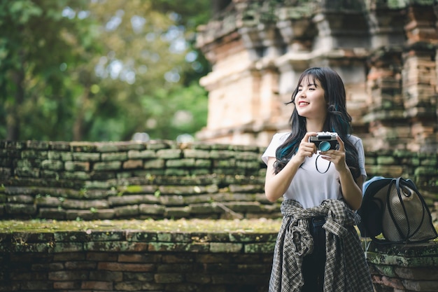 Joven viajero asiático mujer tomando fotos mientras viajaba por el antiguo templo tailandés