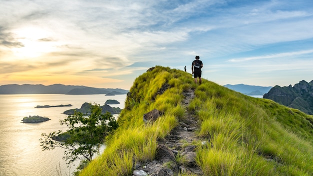 Un joven viajero caminando en la ruta a la cima de la isla de Padar al atardecer. Komodo Nationa