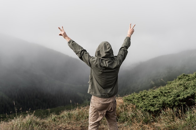 Un joven viajero se para en la cima de la montaña con la espalda y mira el lugar del texto. concepto de turismo.