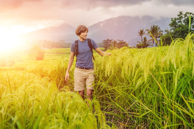 Joven viajero en las hermosas terrazas de arroz de Jatiluwih contra el fondo de volcanes famosos en Bali, Indonesia con luz solar