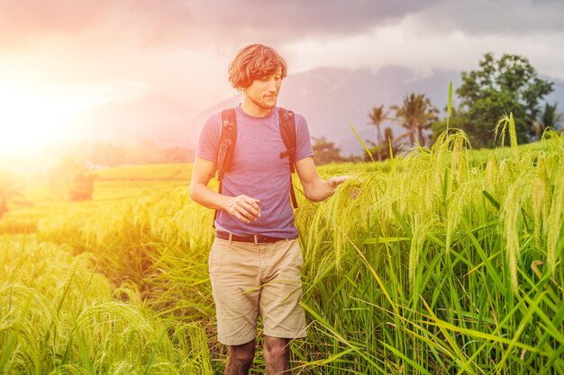 Joven viajero en las hermosas terrazas de arroz de Jatiluwih contra el fondo de volcanes famosos en Bali, Indonesia con luz solar