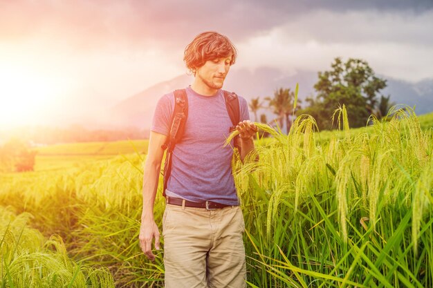 Joven viajero en las hermosas terrazas de arroz de Jatiluwih contra el fondo de volcanes famosos en Bali, Indonesia con luz solar