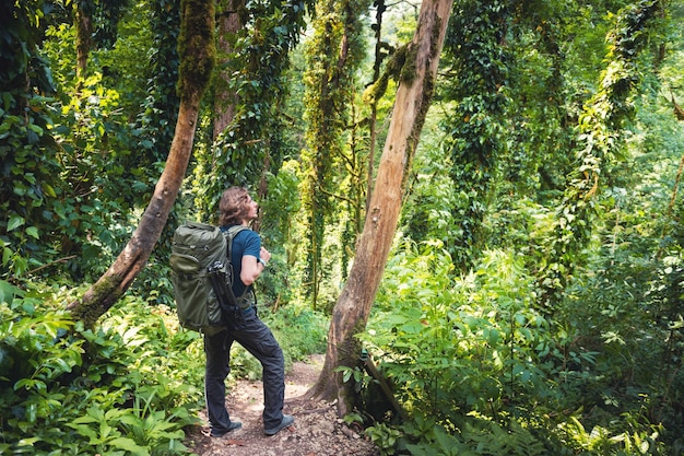 Joven viajero con mochila de senderismo en el bosque tropical Paisaje de verano