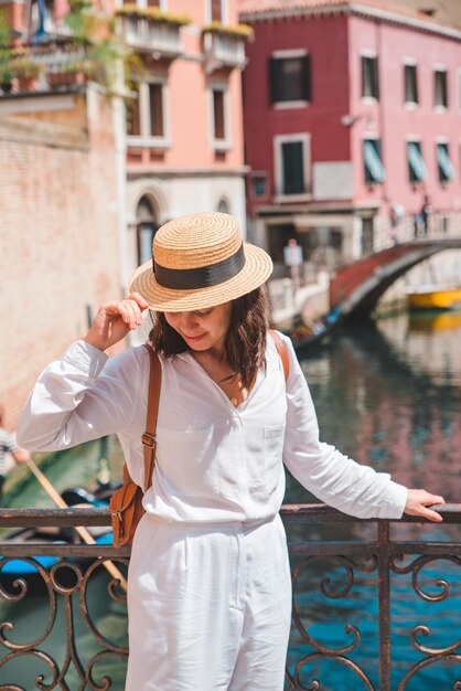 Joven viajero de mujer bonita de pie en el canal cruzado del puente de venecia