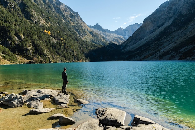 Joven viajero pisa rocas en la orilla del lago de Gaube en los Pirineos franceses