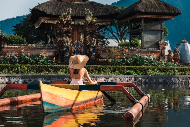 Joven viajero remando en un bote de madera en Pura Ulun Danu Bratan