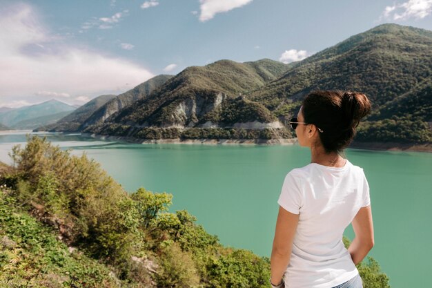 Foto joven viajero se sienta y mira una hermosa vista del embalse de zhinvalskoe, georgia.