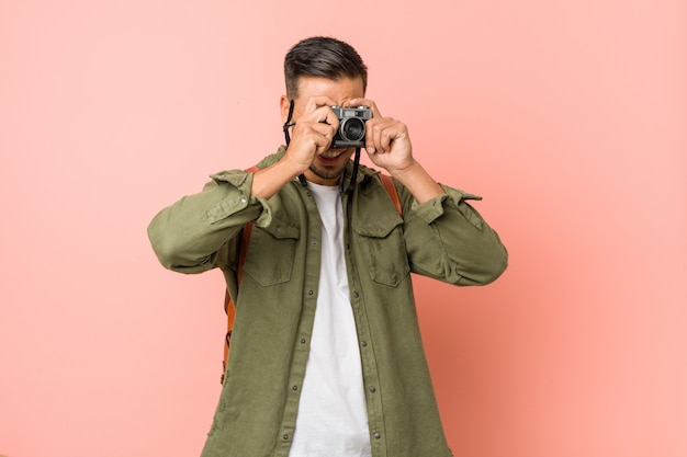 Joven viajero del sur de Asia tomando fotos con una cámara retro.