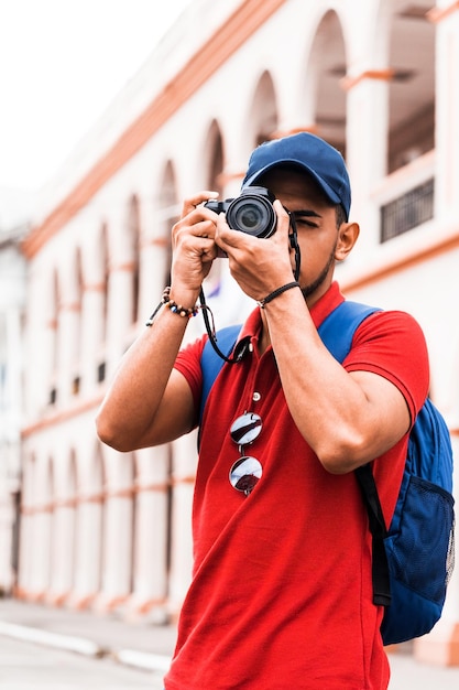 Joven viajero tomando una fotografía al aire libre en la calle Concepto de fotógrafo viajero