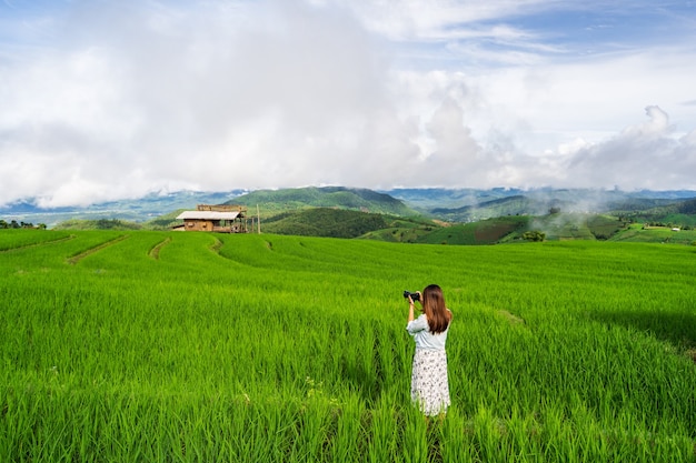 Joven viajero de vacaciones tomando una foto en el hermoso campo de terrazas de arroz verde en Tailandia