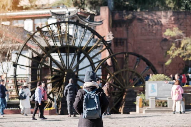 Joven viajero viajando en ruedas de agua gigantes en el casco antiguo de Lijiang, punto de referencia y lugar popular para las atracciones turísticas en Lijiang, Yunnan, China. Concepto de viaje de Asia