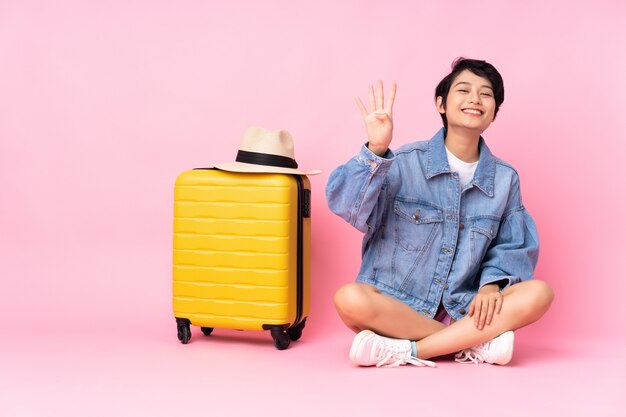 Joven viajero vietnamita con maleta sentada en el suelo