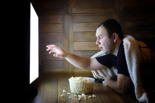 Foto joven viendo la televisión en casa en el suelo y comiendo palomitas de maíz