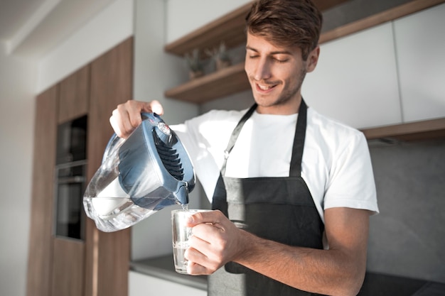 Joven vierte agua limpia en un vaso