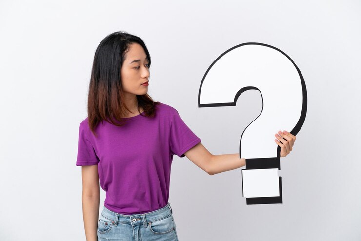 Foto joven vietnamita aislada de fondo blanco sosteniendo un icono de signo de interrogación y con expresión triste