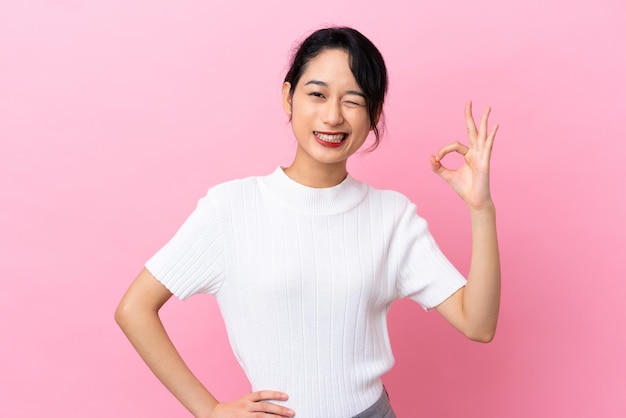 Joven vietnamita aislada de fondo rosa que muestra el signo de ok con los dedos