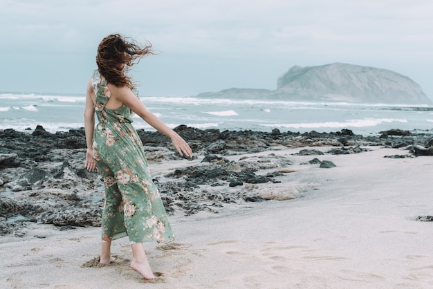 Una joven vista desde atrás con un vaporoso vestido de flores en un día ventoso en la isla de La Graciosa