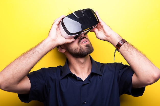 Joven vistiendo un casco de realidad virtual sobre fondo amarillo en estudio