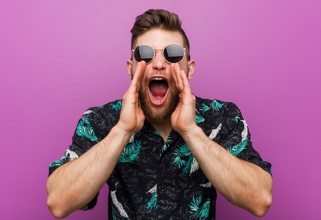 Joven vistiendo un look de vacaciones gritando emocionado al frente.