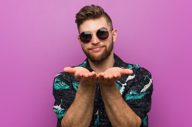 Joven vistiendo un look de vacaciones sosteniendo algo con palmeras