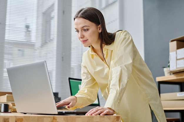 Joven voluntaria agachada en el lugar de trabajo con una laptop