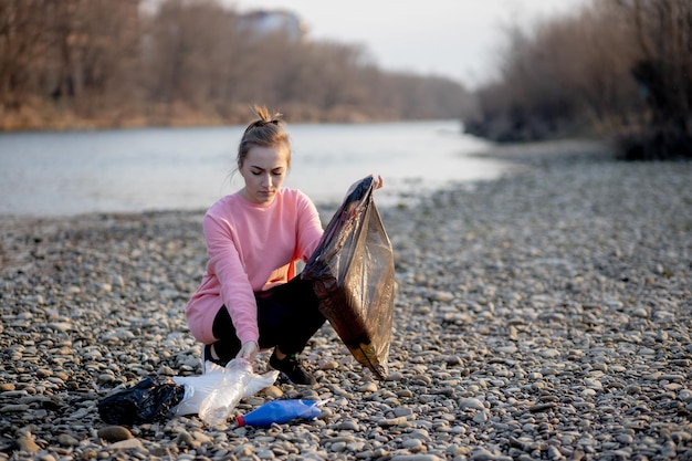 Foto una joven voluntaria recogiendo basura en el río