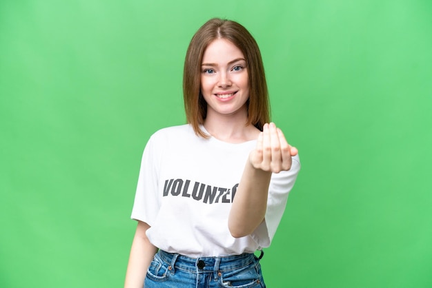 Joven voluntaria sobre un fondo clave de croma aislado que invita a venir con la mano Feliz de que hayas venido