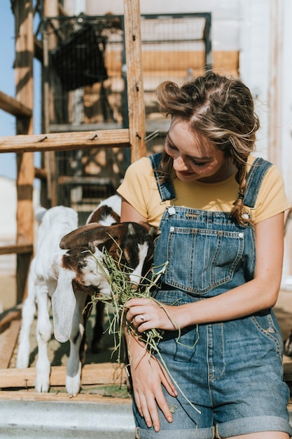 Joven voluntario alimentando cabras bebé