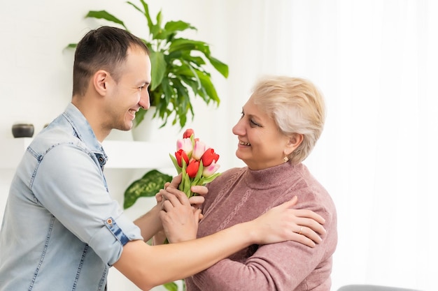 El joven vuelve a casa para sorprender a su madre con un ramo de flores.