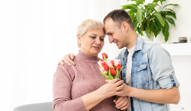 El joven vuelve a casa para sorprender a su madre con un ramo de flores.