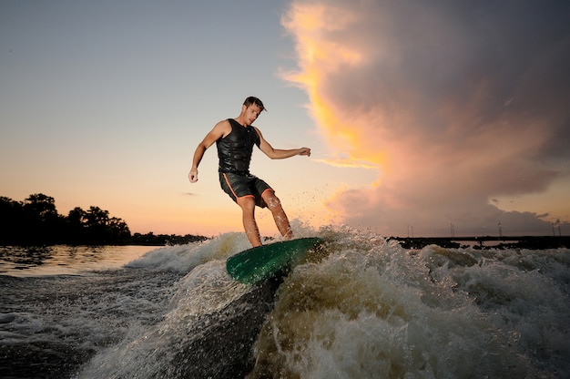 Joven wakesurfing por las olas del río