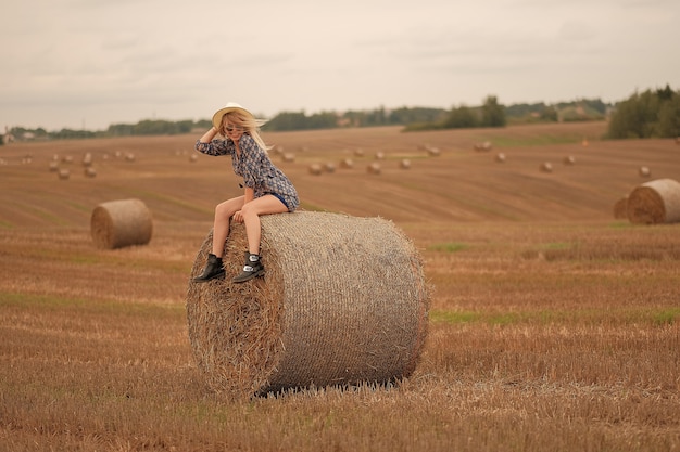 Jovencita descansa en verano y camina por el campo con sombrero y vestido