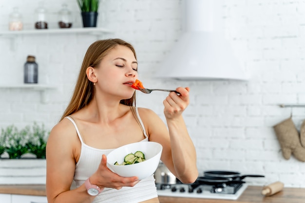 jovencita disfrutando de comida sana en la cocina