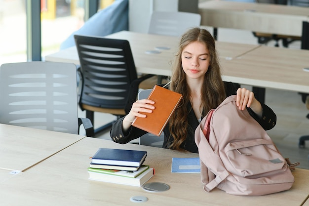 Jovencita estudiando con libros de texto escribiendo ensayos aprendiendo en el aula